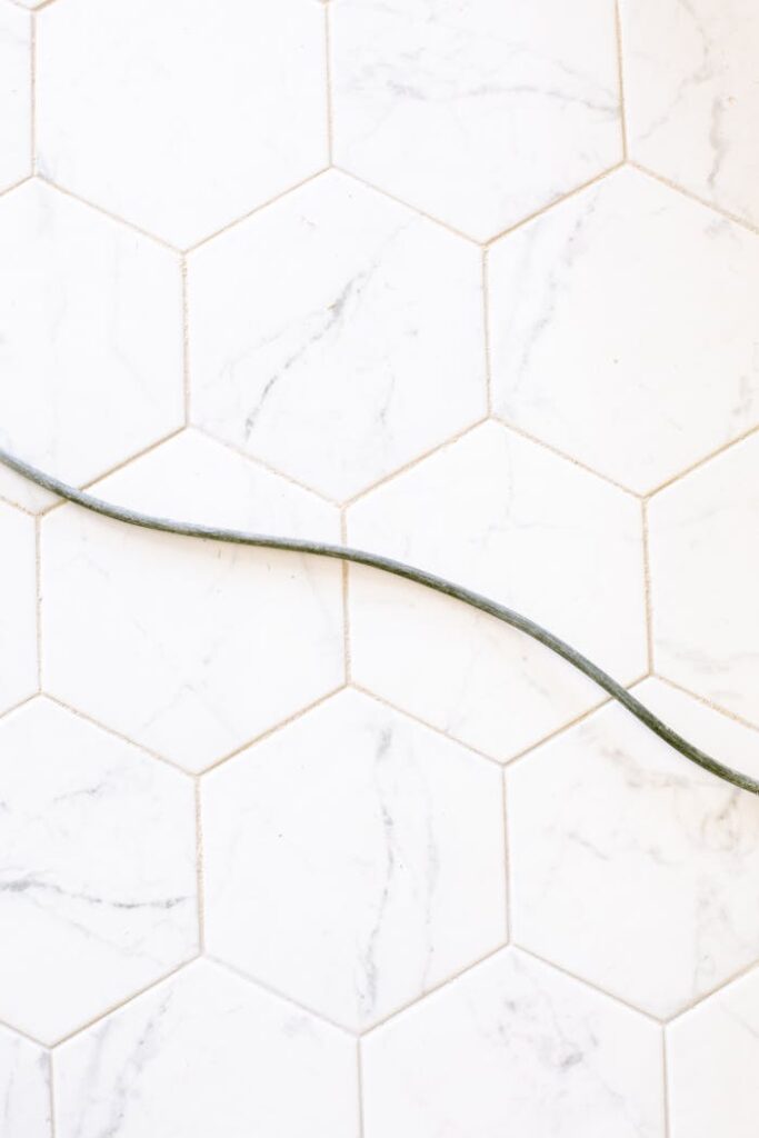 A black cable laid across a white hexagonal tile floor, minimalist design.